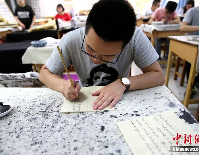 5月21日,在陕西咸阳师范学院于右任书法学院内,数十名大学生手执毛笔