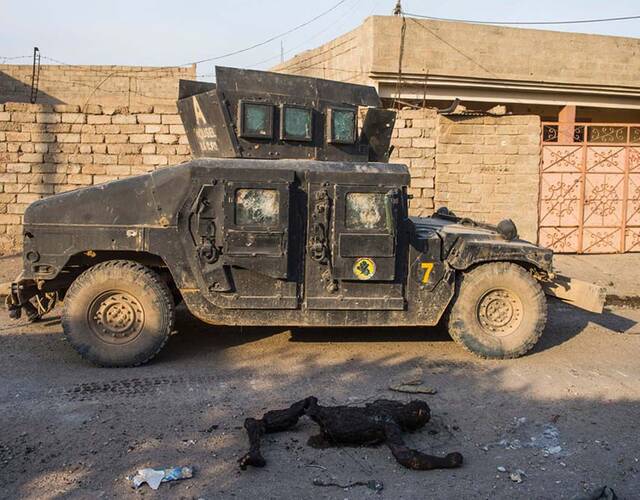 11月13日,一辆伊拉克特种部队的悍马车,经过一具烧焦的伊斯兰国极端
