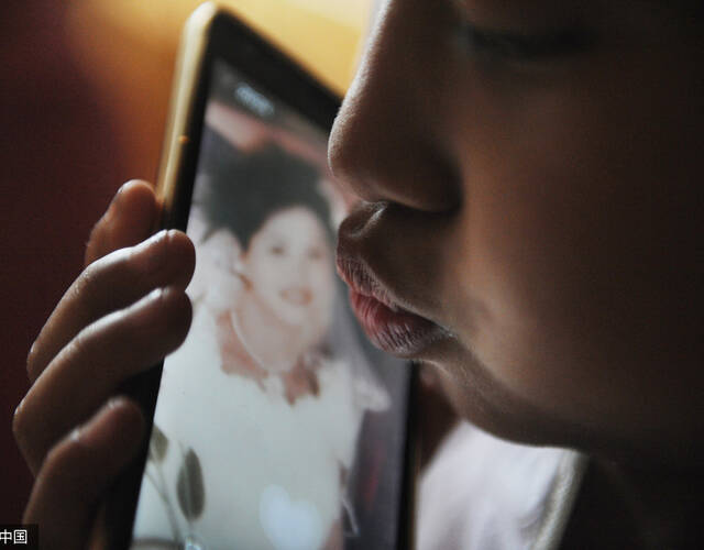 "你想妈妈啦?"记者问.她没有回答,只是对着手机屏幕亲了一口.