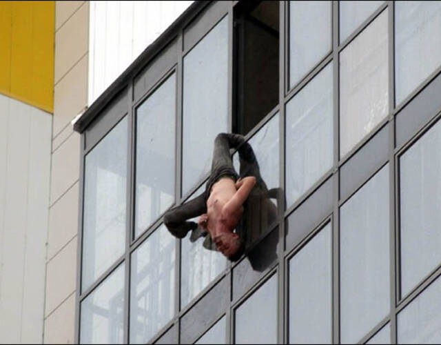 俄罗斯新西伯利亚一名擦窗工人被发现倒吊在大厦15楼窗外,因裤管被