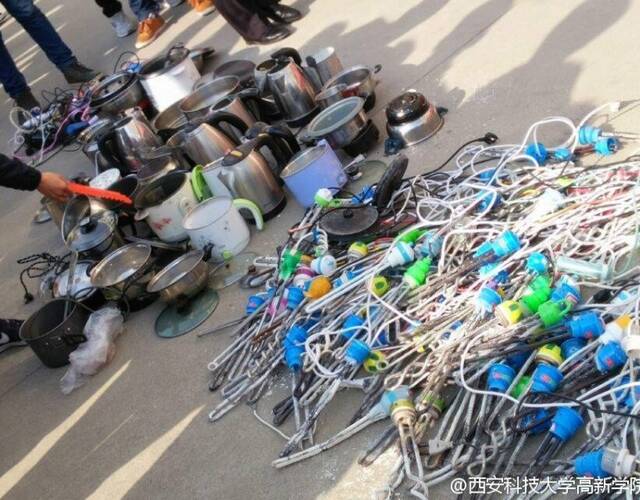 校方收缴的"热得快",烧水壶,电火锅等违规电器有数百件,在教学楼前摆