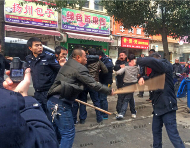 楚天都市报记者迅速赶到现场,4名男子正手持约一米长的木棍击打城管