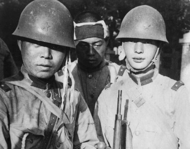 1937年,在中国天津市街道上,一名日本兵展示受伤士兵的头盔.