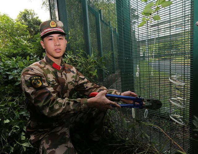 图为边防官兵正在演示涉嫌偷渡人员如何剪开深港边界铁丝网企图逃跑.