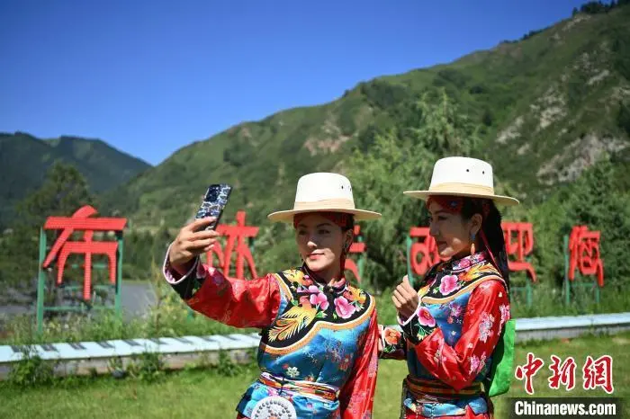 7月7日至15日，2025海外华文媒体甘南行活动在甘肃省甘南藏族自治州举行。其间，来自12个国家和地区的18家海外华媒代表们走进甘南州卓尼县大峪沟。草坪上，身着“三格毛”传统服饰的藏族姑娘翩翩起舞，而小伙子们则踏着鼓点跳起欢快的巴郎鼓舞。据悉，“三格毛”服饰被誉为藏族古代服饰礼仪的“活化石”，因女子常梳三条粗辫得名；巴郎鼓舞则为祈求平安的广场舞蹈。两者均为甘肃省级非物质文化遗产。图为身穿“三格毛”服饰的藏族姑娘。九美旦增　摄