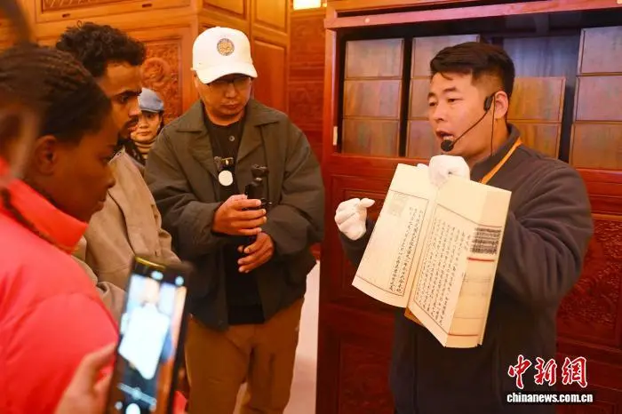 图为工作人员向采访团成员展示介绍《钦定四库全书》　中新社记者　李亚龙　摄