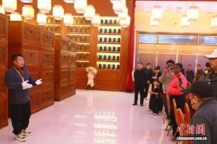 10月19日，“兰州国际传播交流宣传周”联动融合采访活动在甘肃兰州启动，来自加拿大、新西兰、韩国、德国、爱尔兰、马达加斯加等国家和地区的海外华文媒体代表走进了位于甘肃省兰州市永登县的龙王池四库书院参观了《四库全书》。据了解，龙王池四库书院是除文溯阁外，将存世的皇家宣纸图书尽数收藏、抄录、复刻并合璧展出的书院，珍藏着极其珍贵的中华典籍瑰宝，有著名的故宫文渊阁《钦定四库全书》、故宫摛藻堂《钦定四库全书荟要》、承德热河避暑山庄文津阁《钦定四库全书》、浙江杭州圣因寺文澜阁《钦定四库全书》、《永乐大典》残存善本等近百万册典籍图书。图为工作人员向采访团成员介绍《钦定四库全书》。中新社记者　李亚龙　摄