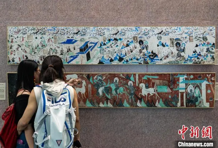 图为观众参观莫高窟第285窟《五百强盗成佛图》（上）和莫高窟第257窟《鹿王本生故事》（下）的石窟壁画复制品　中新网记者　侯宇　摄