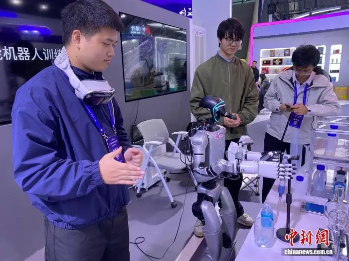 10月18日，中国数博会上，工作人员通过虚拟现实技术操作工业具身智能机器人进行“化学实验”。中新网记者 裴国荣 摄