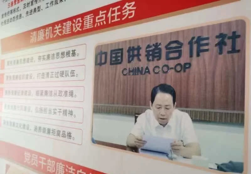 梧州市供销社联合社的宣传栏内，黄东明在会上讲话的图片。