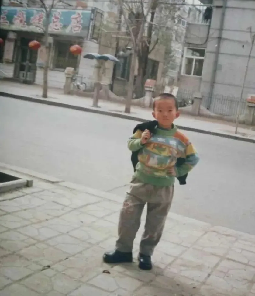 ◎ 童年的小奇，摄于妈妈理发店门口