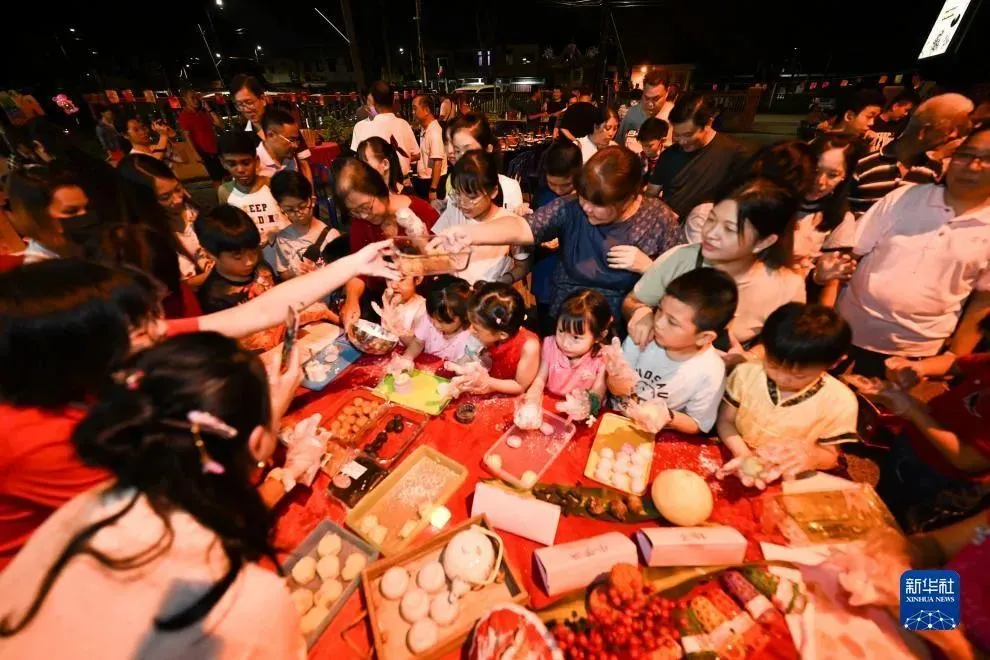 9月27日，在马来西亚马六甲州丹绒吉宁举办的中秋晚会上，人们参加制作月饼活动 图：新华社