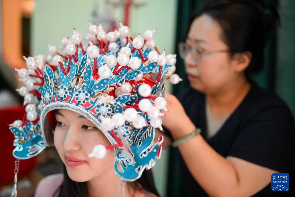 9月18日,在吉尔吉斯斯坦奥什国立大学孔子学院,一名教师为学生佩戴晚会活动上用的头冠。新华社记者 李任滋 摄