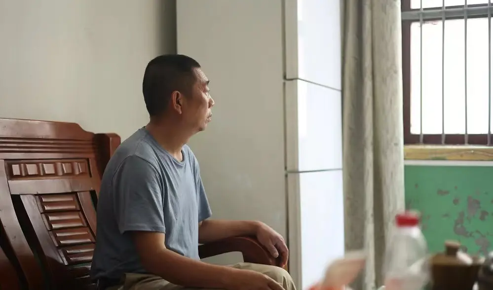 ·章荣高坐在客厅，凝视窗外。原霞/摄